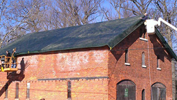 State Parks protected the DeVeaux Woods Carriage Barn roof (above) in 2011 following a massive public outcry over its plan to destroy the historic building. The flimsy covering now hangs off the building (below) months after a windstorm damaged it.